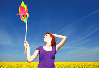 Young girl with wind turbine at rape field.