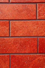 Dark red brick tile wall closeup view.