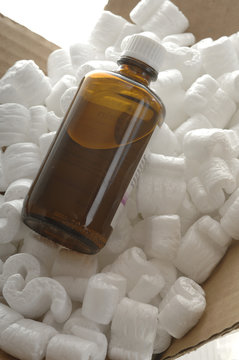 Flasche im Karton mit Styroporchips vor Weiss