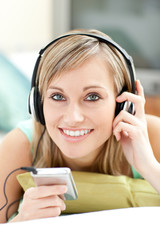 Attractive young woman listening music lying on a sofa