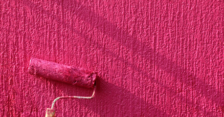 Painting of red wall with paint roller