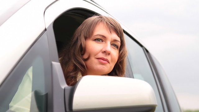 Beautiful, woman opening window and looking out of car waving