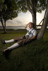 Exhausted golfer resting under a tree.