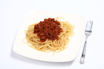 Pasta with bolognese sauce on a plate and a fork on white