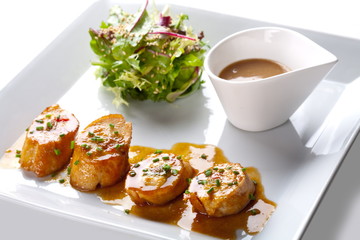 Scallops with salad and sauce on white plate