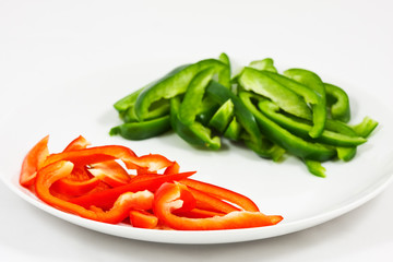 Chopped red and green peppers on white