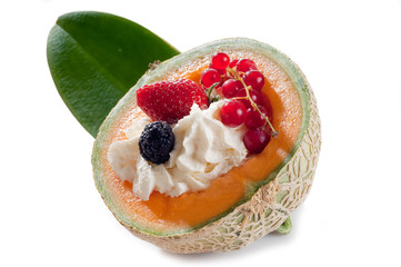 mix of berries fruits over whipped cream on open melon
