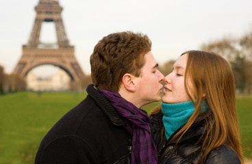 Happy couple in love in Paris kissing near the Eiffel Tower