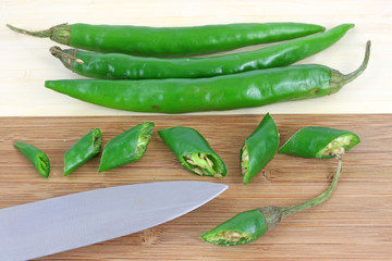 Long green hot peppers on wood cutting board