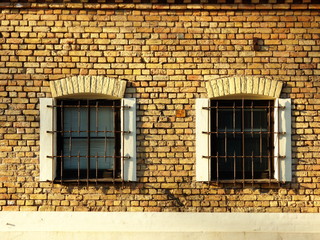 Yellow brick wall with two barred windows