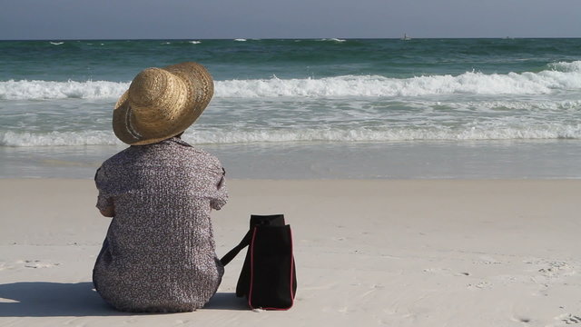 Woman Sitting On Beach With Bag