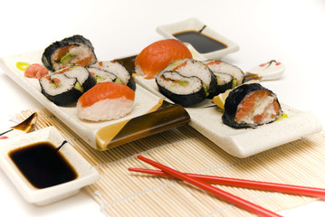 Sushi with chopsticks against white background.