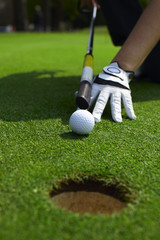 Aiming a golf ball to a hole on a putting green - 22624370