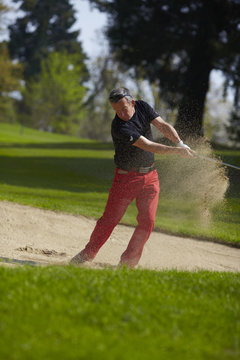 Golfer man in the bunker after swing with sand in the air