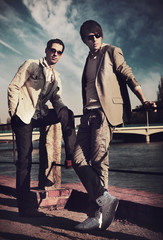 Two handsome friends posing on a city promenade