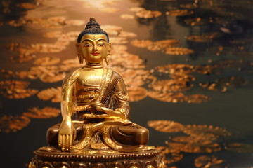 Fototapeta premium Buddhafigur, Statue im Licht aus Gold am Teich im Garten