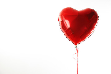 Red heart ballon with red and white strings on white fond