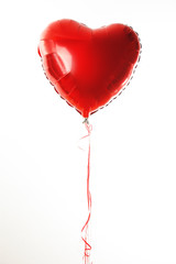 Red heart ballon with red and white strings on white fond