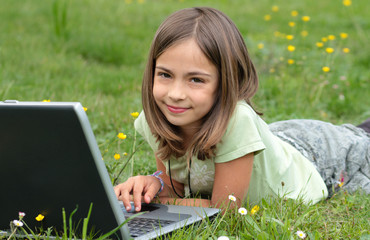 fillette faisant de l'ordinateur dans l'herbe