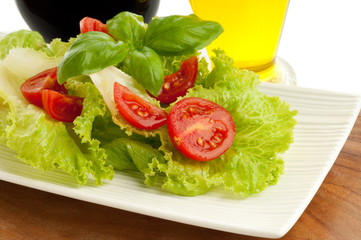 tomato and lettuce salad with bottle of oil and vinegar