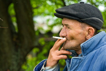Poor old man smoking outdoors