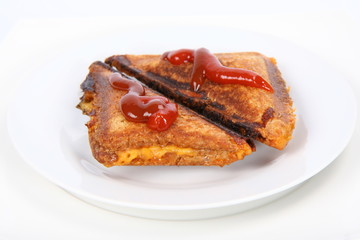 Toasted sandwich with cheese decorated with ketchup on a plate
