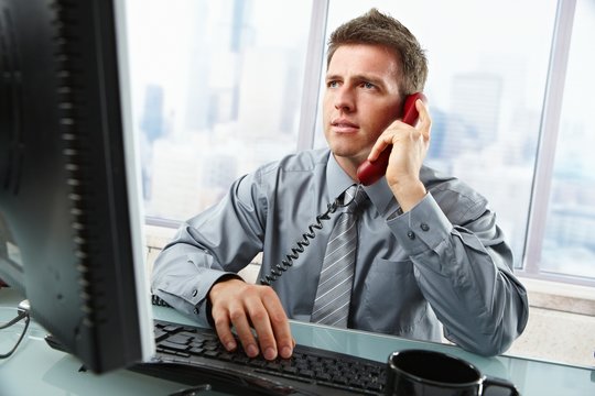 Businessman talking on landline phone in office
