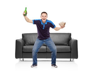 Sport fan with beer bottle and popcorn in his hands