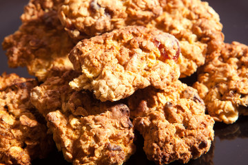 Home made oat and fruit cookies piled on black plate