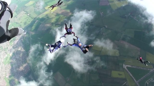 Five skydivers in freefall falling through clouds
