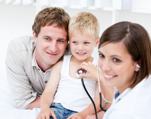 Portrait of beautiful female doctor examining a little boy with