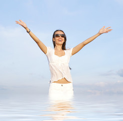 A young and happy woman is standing in the water