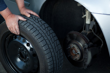 mechanic changing a wheel of a modern car (color toned image)
