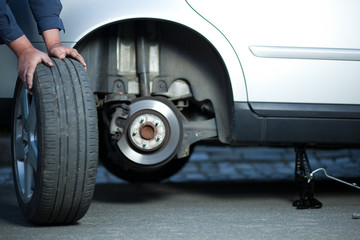 mechanic changing a wheel of a modern car (color toned image)