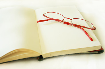 Notebook made of a red skin and glasses