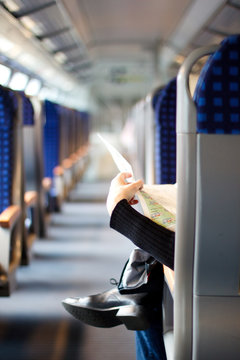 Woman reading newspaper in train cabin