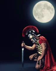 Wall murals Knights Legionary soldier standing on a knee at night time