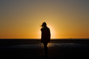 Fototapeta na wymiar Silhouette of a girl on the beach at a sunset