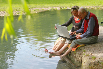 Alter Mann und junge Frau arbeiten am Laptop im Grünen