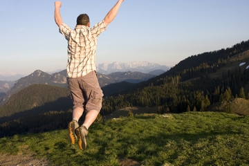 Fototapeta premium mann spring vor freude in den alpen