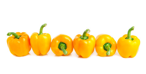 border of bright yellow peppers isolated on white.