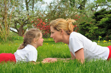 Fototapeta premium Young mother and daughter laying on the grass