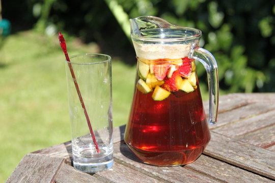 jug of Pimms and lemonade cocktail with fruit and empty glass
