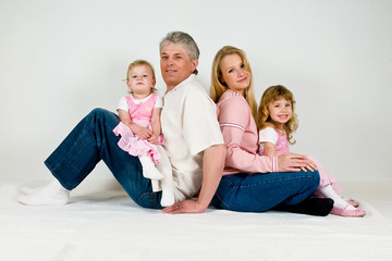 Happy family with two daughters sitting on parent's laps
