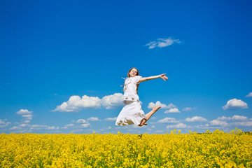 beautiful young woman jumping on field in summer