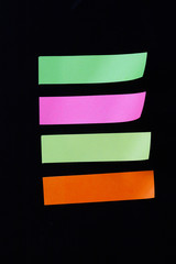 colored sticky notes isolated on black background .