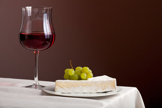 Glas Rotwein und Camembert mit Trauben