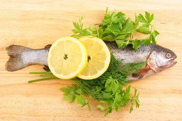 Raw fish with lemon and parsley on wooden background