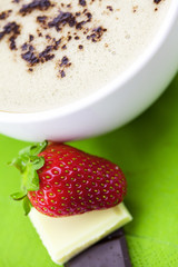 cup of cappuccino with chocolate and strawberry on a napkin