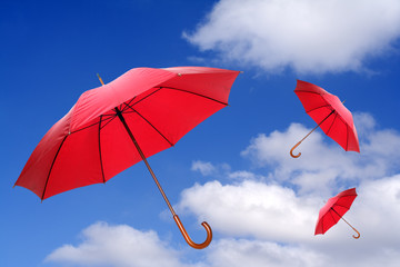 Three red umbrellas flying in a rich blue sky.